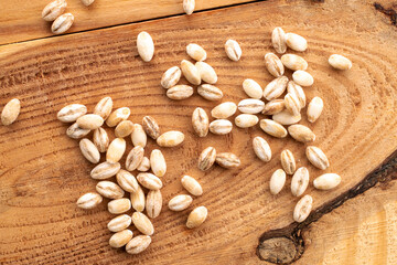 Organic pearl barley on a wooden table, close-up, top view.