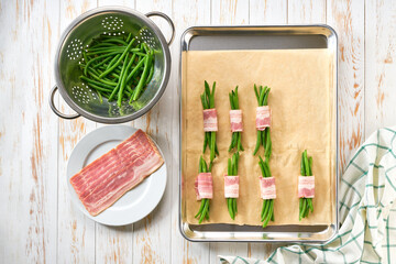 bundle of green beans wrapped in bacon on baking tray, preparation for baking, top view.