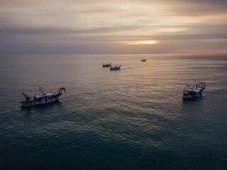 fishing boats in the middle of the sea fishing for clams at dawn