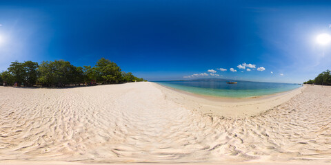 Island with a sandy beach and azure water surrounded by a coral reef and an atoll. Great Santa Cruz...