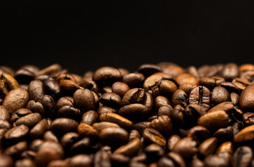 Espresso roasted coffee beans isolated in black background close up