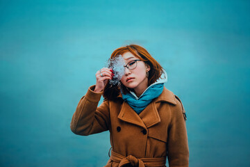 Portrait of a beautiful young red-haired Asian woman holding a transparent piece of ice in her hand, standing against the background of a frozen sea in winter. North.