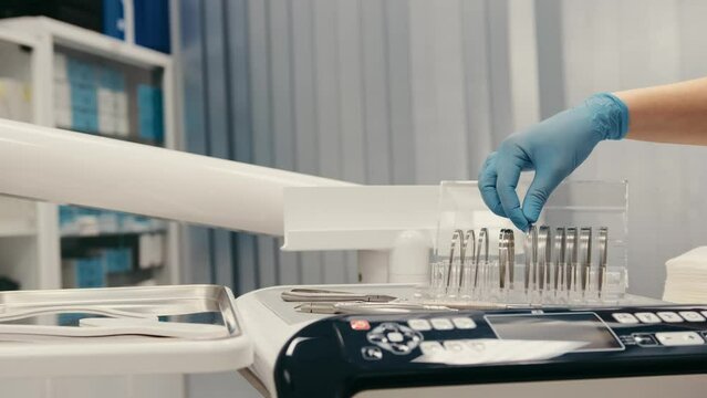 Close-up dentist's hand chooses an orthodontic archwire for the patient's braces
