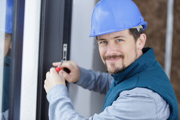 service man installing window with screwdriver