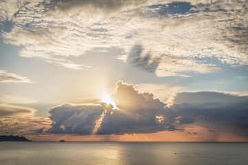 Spectacular sunrise with the sun through the clouds on the sea. Sun reflecting in the clouds. Sunbeams cast shadow on the cloud. 