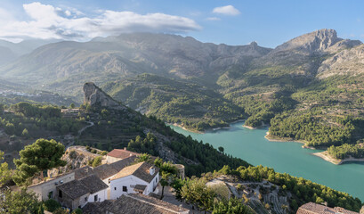 Fototapeta na wymiar Views areas of the Guadalest reservoir with crystal clear turquoise waters between mountains with some houses nearby. Alicante. Spain