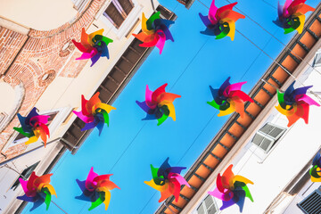 Colored rainbow fan hanging between buildings, street decoration and sun protection