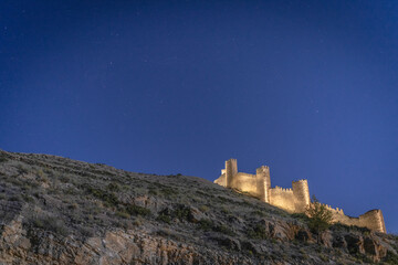 Illuminated castle on top of the mountain in the village of Albarracin at starry night. Teruel. Spain