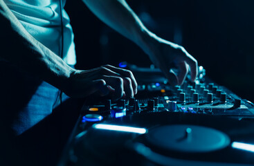 Techno party DJ playing music with sound mixer and turntables. Club disc jockey mixing musical...
