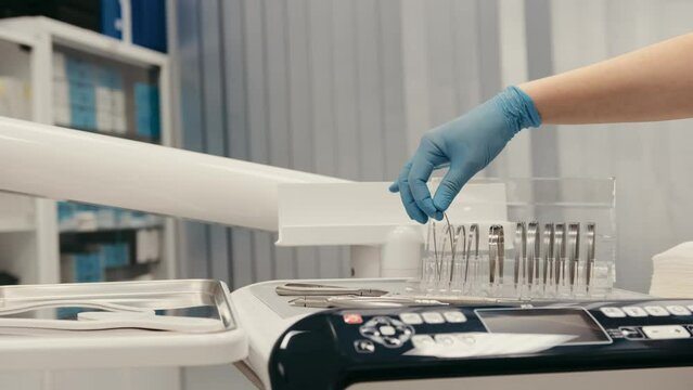 Close-up dentist's hand takes an orthodontic archwire for braces