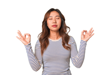 A young chinese woman relaxes after hard working day, she is performing yoga.