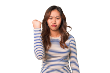 A young chinese woman showing fist to camera, aggressive facial expression.