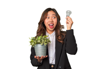 A young Chinese businesswoman holds a lightbulb and plant, embodying her innovative ideas and commitment to sustainability and the environment.