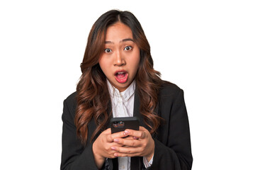 A young Chinese businesswoman looks surprised while glancing at her phone, perhaps receiving...