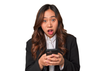 A young Chinese businesswoman looks surprised while glancing at her phone, perhaps receiving unexpected news or a message that has left her amazed.