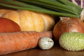 Vegetables from the garden on a wooden table forming a still life of vegetables and greens.