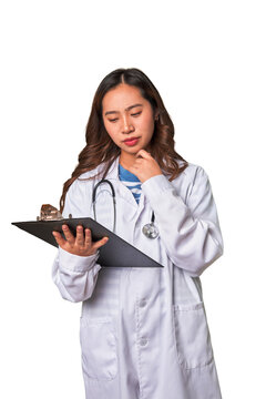 Attentive Chinese woman doctor reading patient report with professional care.