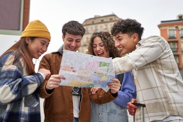 A diverse group of friends laughing and planning their Madrid sightseeing adventure with a city map in hand.