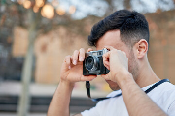 Young caucasian man capturing memories with his vintage camera in the park.
