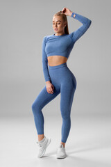 Athletic girl on gray background. Fitness woman in leggings - 587750477