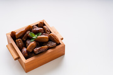 Dried dates fruit in wooden tray isolated on white background. 
