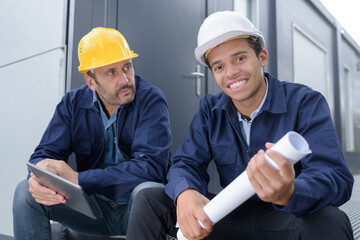 two engineers with blueprint outdoors