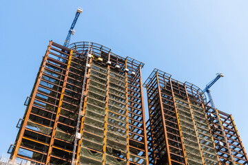 Building construction site and cranes with a blue sky background.