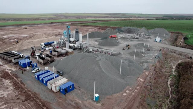 Tippers at gravel heaps and rock processing tower in mining pit bird eye view. Construction materials manufacture in large quarry