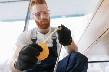 Fototapeta premium Plumber man at work in bathroom, fix repair service wraps fluoroplastic sealing material tape around faucet hose. Concept install plumbing