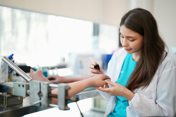 Fototapeta premium Female physiotherapist in workshop molding dummy of prosthetic human body parts.