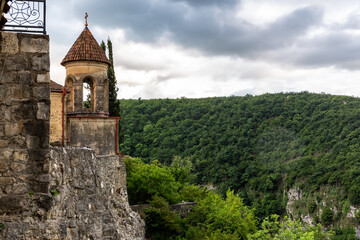 Fototapeta na wymiar Belfry of Motsameta monastery, XI century medieval stone orthodox church located on a cliff among lush forests in Georgia, Imereti Region.