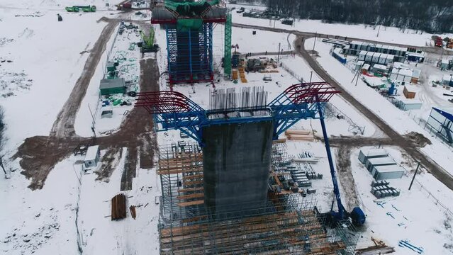 Cement bridge support with metal frame and scaffolds at construction site on winter day aerial view. Element of future transport way