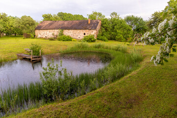 A house in the woods with a pond in the foreground
