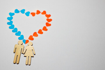 Male and female love LGBT. In marriage, family icons. Couple of lovers. A woman and a man are holding hands. Wooden people with paper blue and red hearts