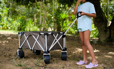 Little asian girl pulling the trolley at Camping park in Malaysia . Recreation and journey outdoor activity lifestyle.