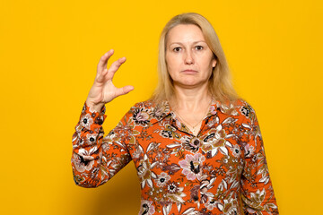 Caucasian blonde female with raised hand in the form of a claw ready to attack her prey, she is...