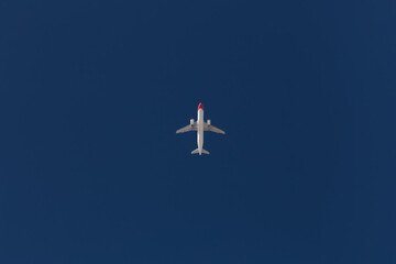 Bottom up view of a commercial jet airliner flying on clear blue sky with lot of copy space