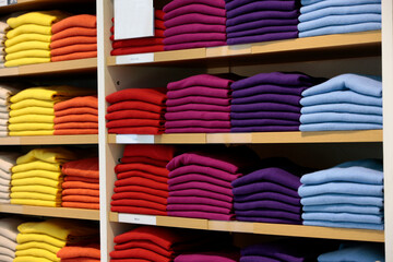 Stacks of colorful cashmere sweaters on shelves in retail store.