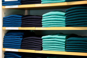 Stacks of colorful cashmere sweaters on shelves in retail store.