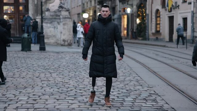 Prosthetic leg, Disabled man, Street walking. Young disabled man with prosthetic leg walks down street.