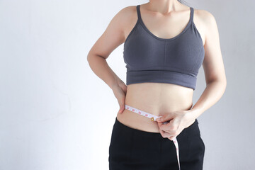  A woman measures her waist with a tape measure