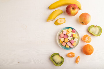 Various fruit jelly chewing candies on white wooden. apple, banana, tangerine, top view, copy space.