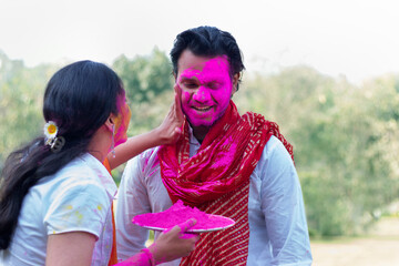 Woman putting colour on a man's face during holi celebration