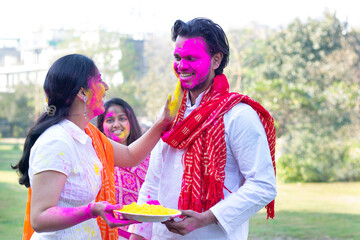 Woman putting colour on a man's face during holi celebration