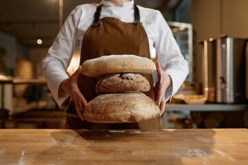 A baker holding stack of freshly baked bread