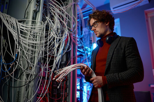 IT man with bunch of cables in hands in server room