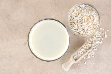 A glass of oat milk and oatmeal on beige background. Top view. The concept of alternative lactose-free dairy products.