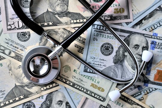 Stethoscope laying on money - Medical costs, doctor's bills, cost of insurance
