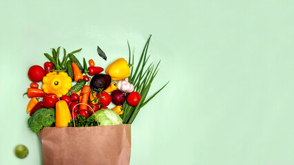 Set of fresh vegetables in a paper bag on a green background.