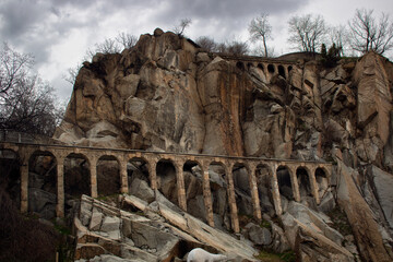 ancient roman aqueduct with arches between the rocks and crags of an old medieval epic fantasy city...